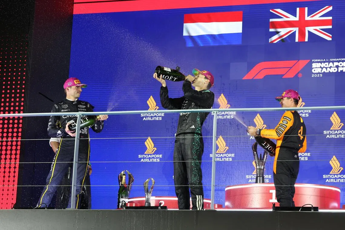 （左起）亚军费斯塔彭、冠军拉塞尔和季军诺里斯，在台上喷香槟庆祝。（唐家鸿摄）