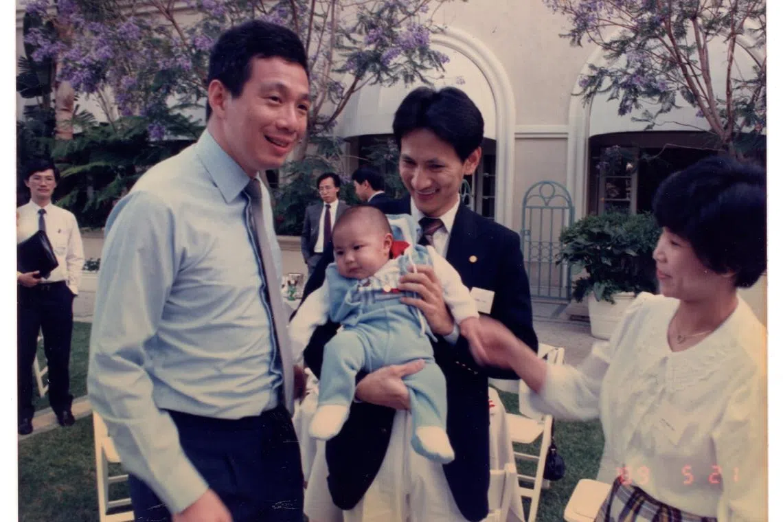 1989年，时任贸工部长李显龙访美期间，在加州会见了旅居美国的新加坡留学生。洪振南（右二）当时抱着只有三个月大的儿子洪家豪（左二）与总理见面，照片也登上报纸。（受访者提供）