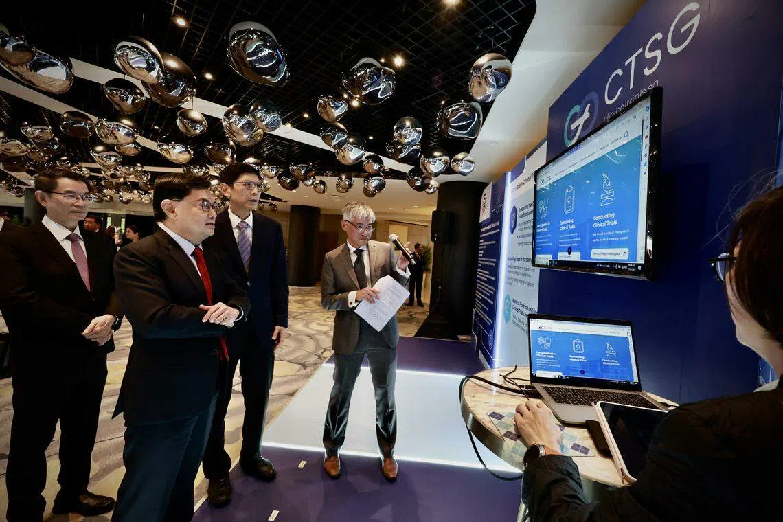 副总理王瑞杰（左二）星期二在研讨会现场，听新加坡临床研究与创新联盟首席执行官孙光伟兼职副教授（左四）介绍新启动的新加坡临床试验网站。在场的包括联盟董事长林建伟教授（左一）和国家研究与开发事务常任秘书陈祝全教授（左三）。（特约陈来福摄）