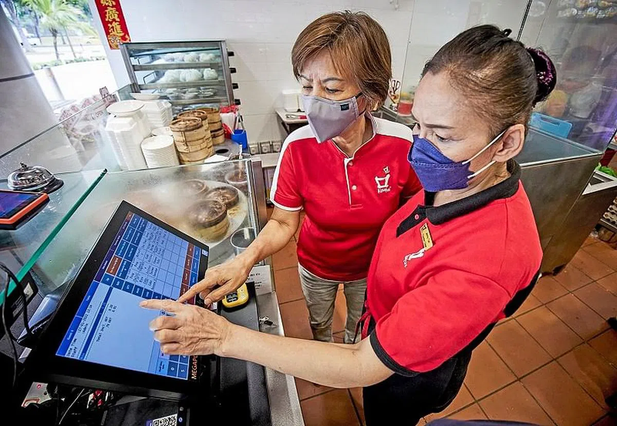 颜秀枝（左）当初积极学习在工作上的科技运用，现在已能在店面教导其他人。（图／新报业媒体）