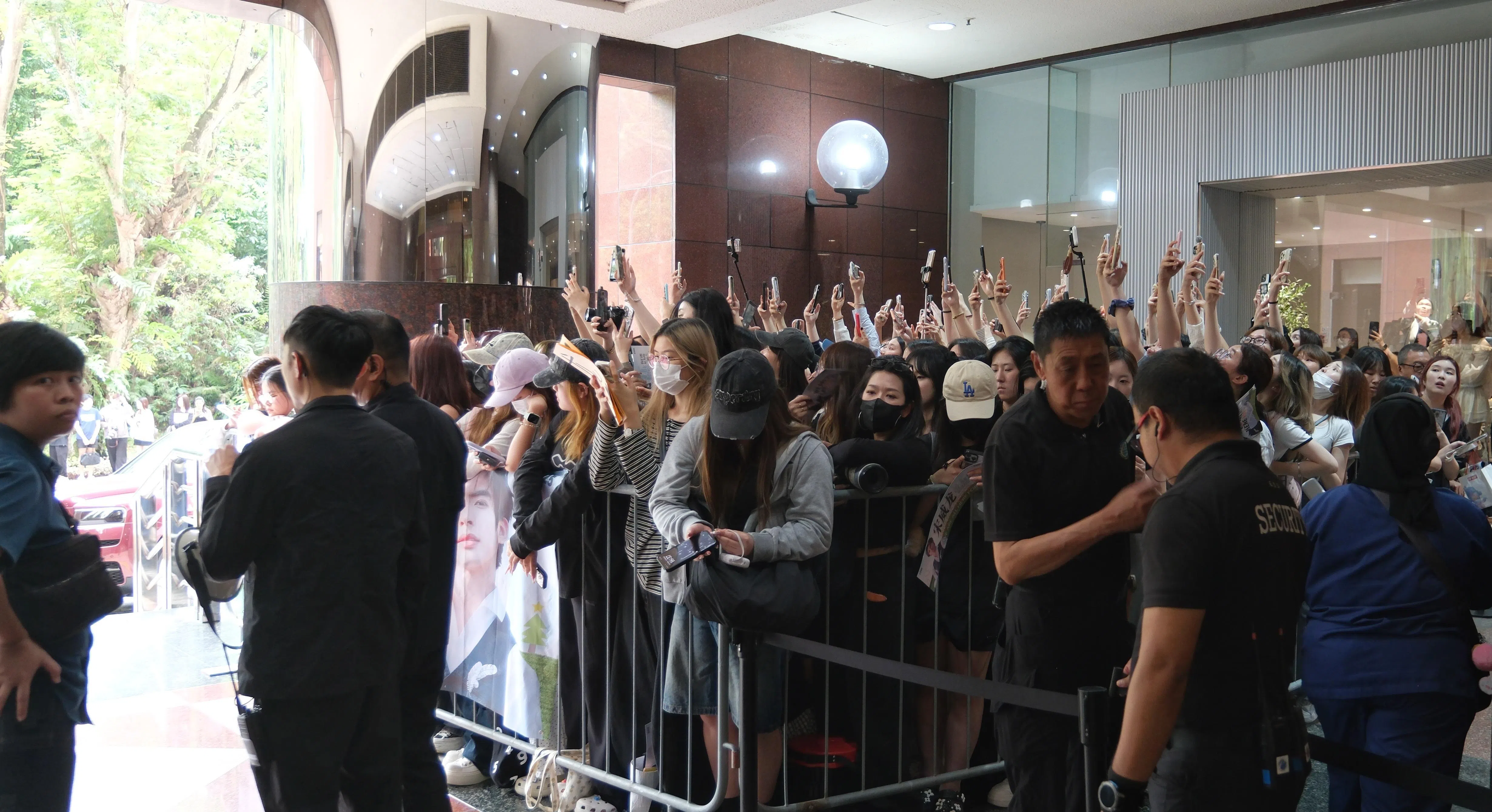 一有动静，粉丝便立刻举起手机，生怕错过偶像的身影。（曾坤顺摄）
