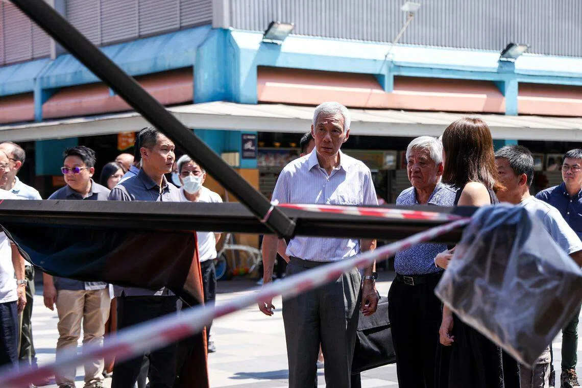 也是宏茂桥集选区议员的国务资政李显龙（中）到场向咖啡店店主了解火患造成的损失，以及保险事宜。（白艳琳摄）