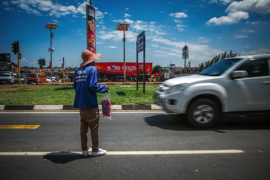 街头小贩拎着商品穿梭于车流寻找“商机”。（叶振忠摄）