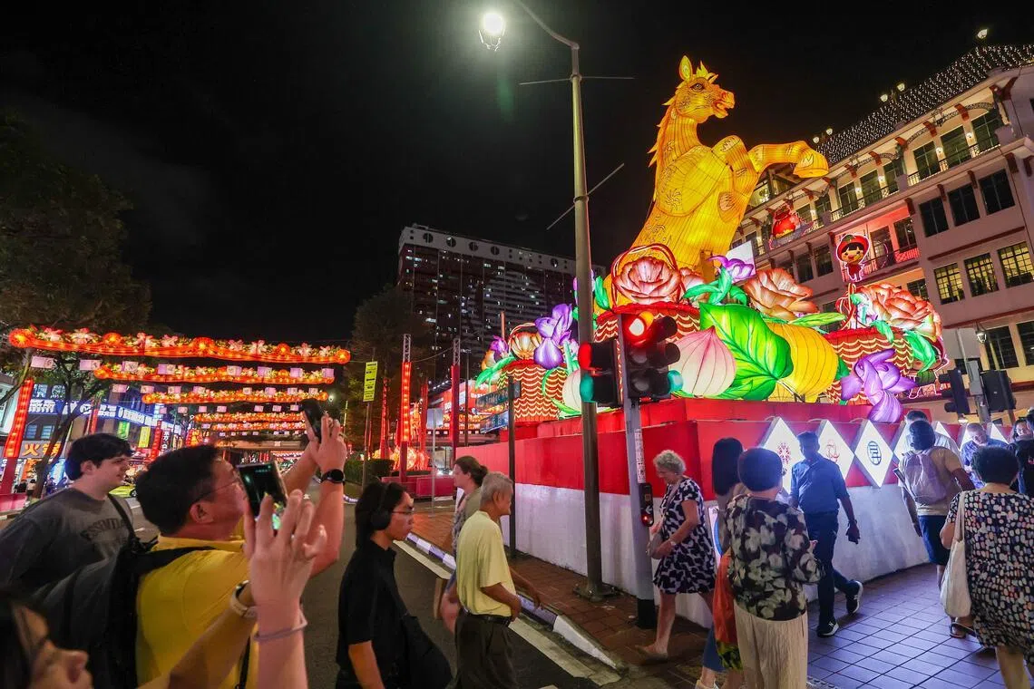随着暮色降临，牛车水马年新春灯饰亮起，8.8米的“金马”格外吸睛。（陈斌勤摄）