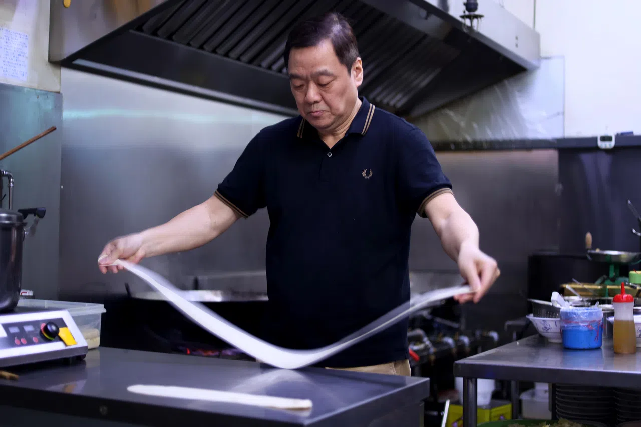 黄土地西安小吃的创办人纪鹏示范制作biáng biáng面，其面因制作时发出biáng biáng的声音而得名。（龙国雄摄）