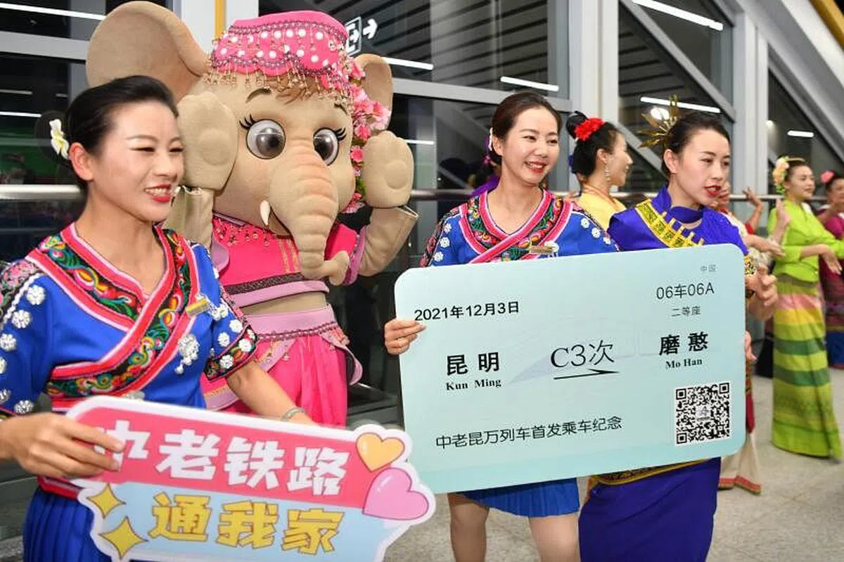 12月3日，中老铁路全线开通运营，西双版纳傣族自治州举行具有民族特色的欢迎仪式，迎接首批乘坐首发列车的旅客抵达西双版纳景洪市。图为列车员在西双版纳站与当地迎宾合影。（中新社）