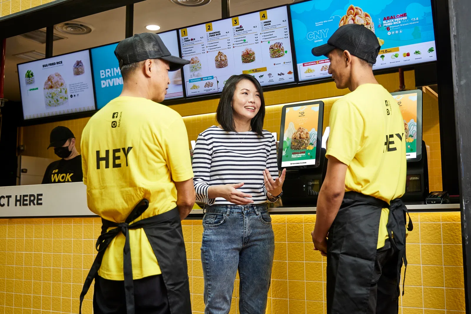 WOK HEY财务总监林诗婷（面对镜头者）表示，公司会鼓励员工向顾客介绍线上订餐的选项，无须排队点餐，也可即时取餐。这不仅提升了顾客体验，又优化了工作环境，实现了顾客与员工共赢。（图/新报业媒体）