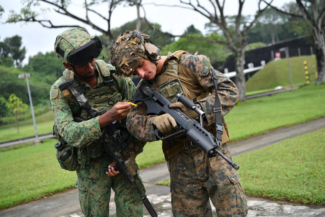 新美两国军人针对各自武器——新加坡SAR 21步枪和美国M27自动步枪相互交流，学习操作。（国防部提供）