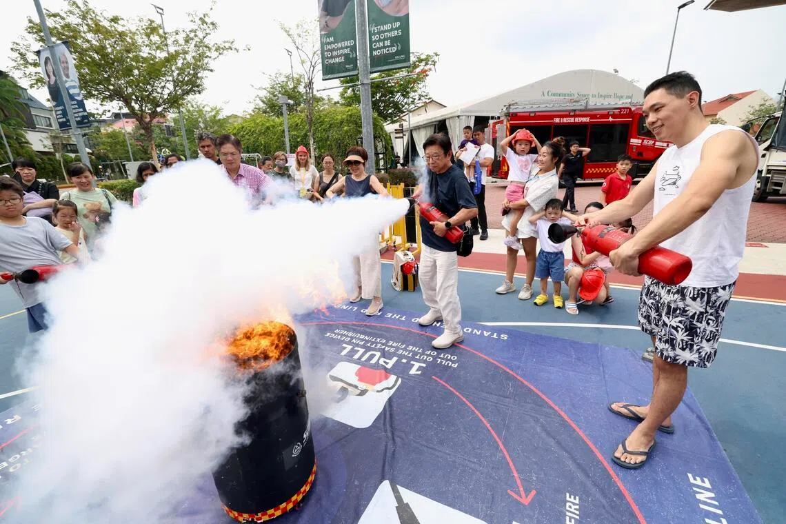 科技公司经理龙杰胜（右一）在3月29日的如切紧急应变日上，向家人演示使用灭火器。　（陈斌勤摄）