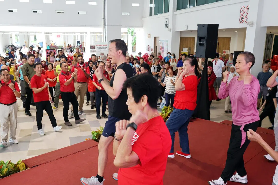 在基武吉社区举办的保健嘉年华会现场，健身教练带着台上和台下的居民一起强身健体，保持活跃。（梁麒麟摄）
