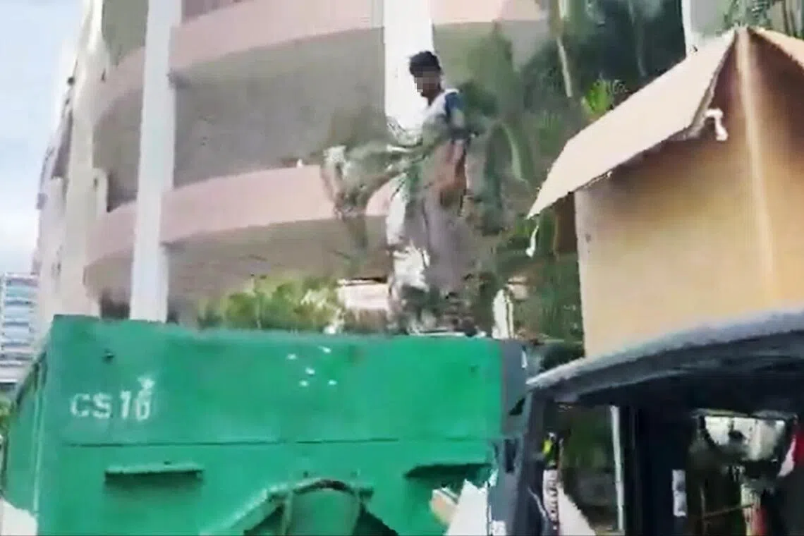 在举报视频中，一名工人被叉车运送到垃圾箱顶后，站在高处作业。（视频截图）