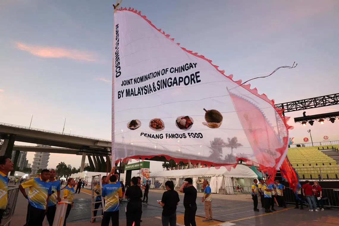 槟城大旗鼓队特别制作10公斤重、40尺高和32尺宽的全新巨型白旗，旗面印上妆艺申遗标语。（萧紫薇摄）