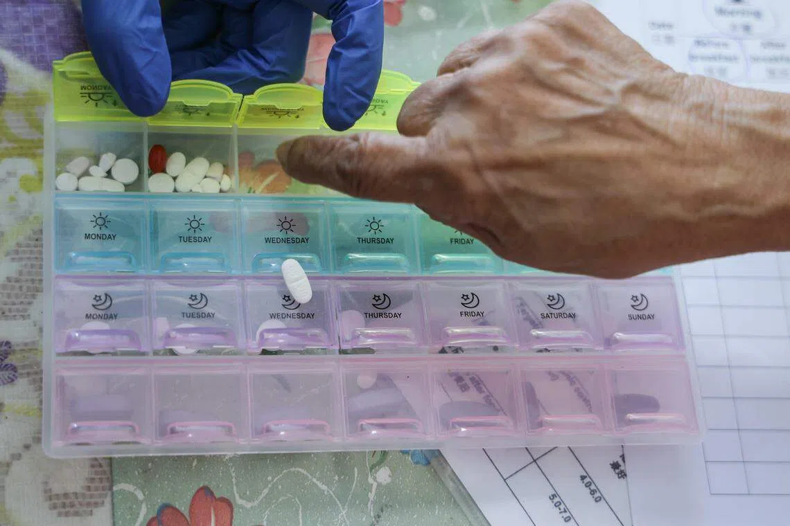 何淑娟进行家访时，检查病患特丽莎药盒中的药物是否正确。若有偏差，她也会进一步查询患者的用药习惯和分辨不同药物的能力等。（白艳琳摄）