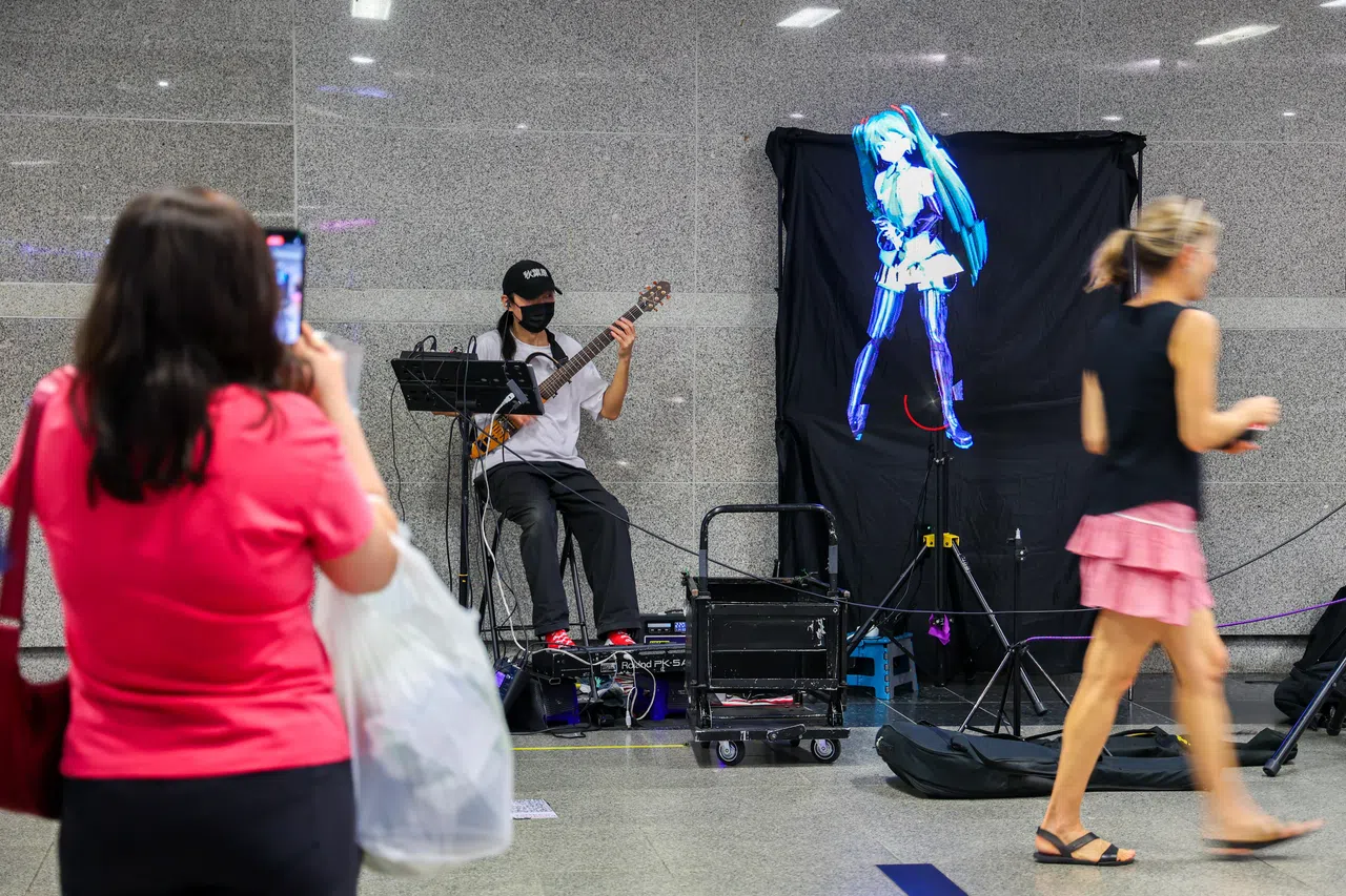 街头艺人“The One Boy Band”一人操作乐器与全息装置，配合虚拟歌姬的影像打造表演空间。（林明顺摄）