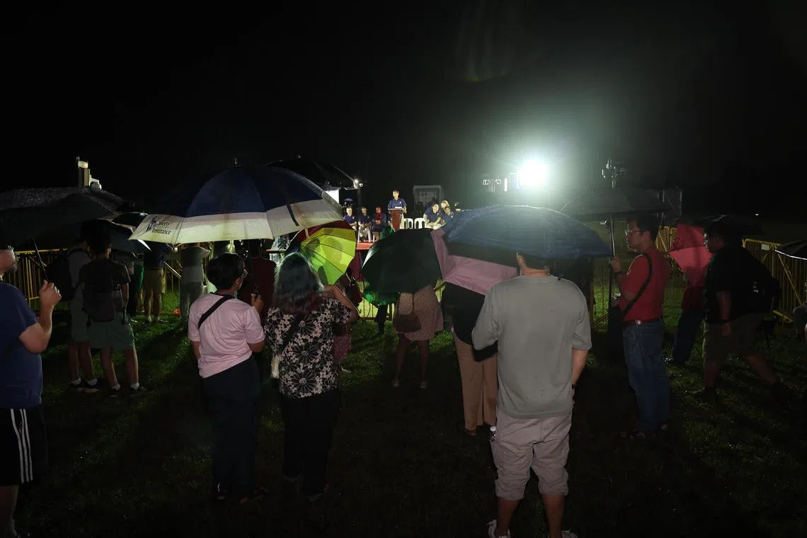 尽管下起细雨，仍有不少公众撑伞到裕华园地铁站旁的文礼大道草场，听红点同心党候选人发表演讲。（邬福梁摄）