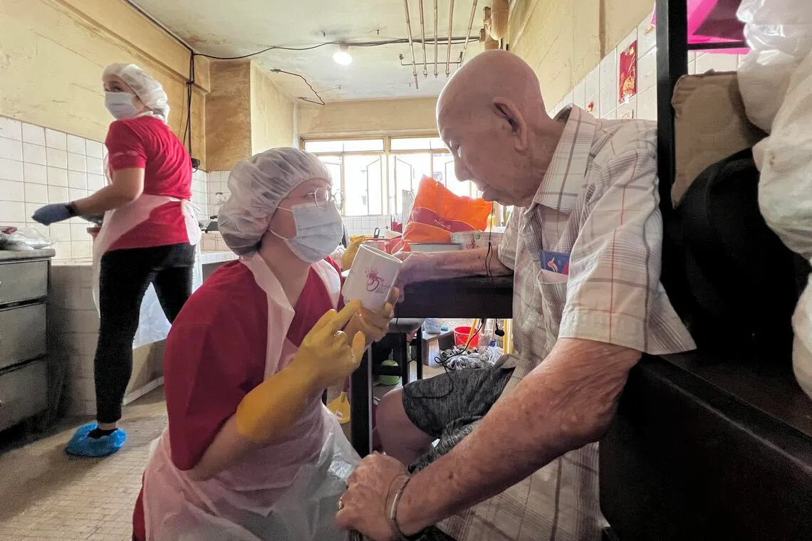 黄廷方综合医院高级注册护士莱斯利 （Lesley Marie，左）正在为93岁的独居老人陈显基（右一）整理杂物和洗刷环境，协助老人营造安全整洁的居住环境。另一名同医院的高级注册护士周祖金（左二）蹲下身来与陈显基沟通，了解老人家的需求。（黄廷方综合医院提供）