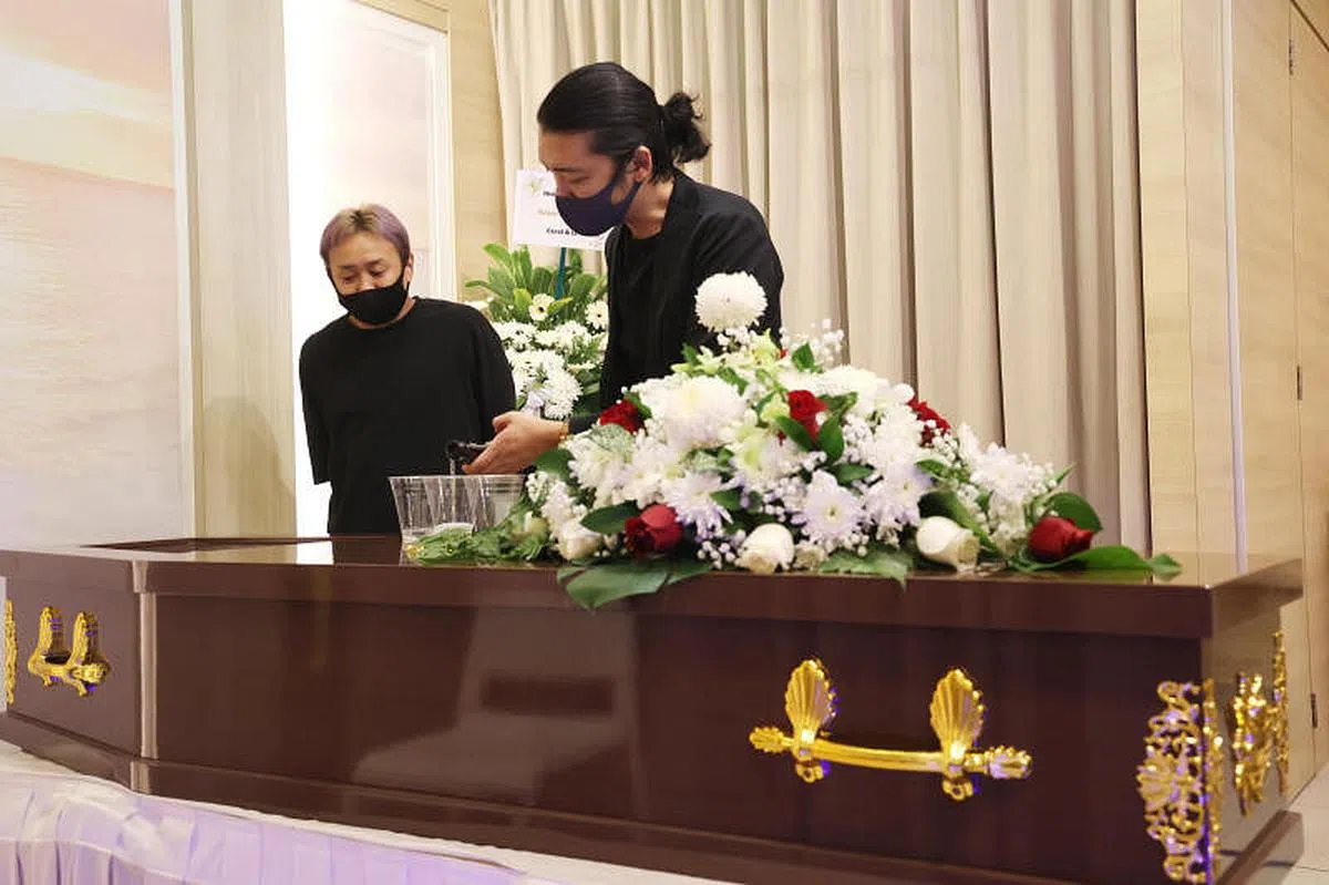 田中秀幸的朋友带着酒前往灵堂悼唁，在棺木前倒上三杯酒，与他“共饮”一杯，为他送行。（邝启聪摄）