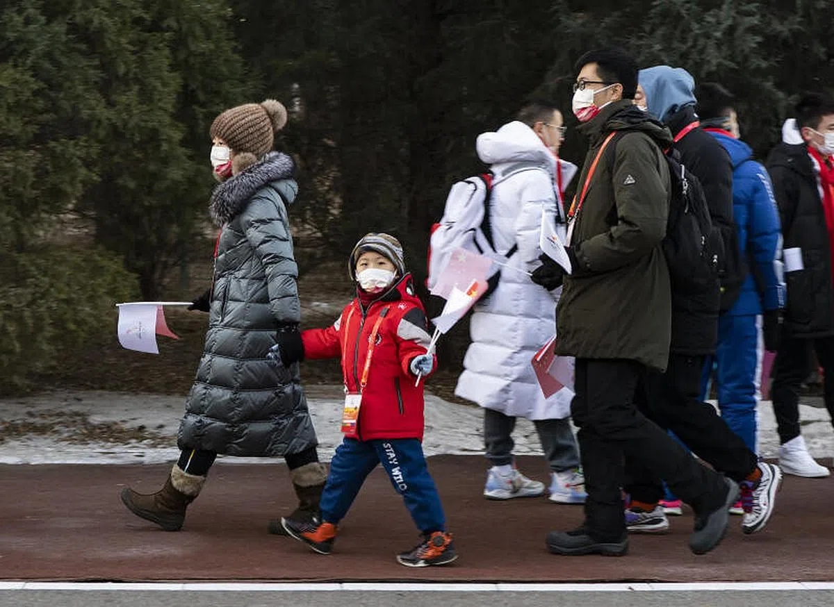 一名小朋友在家长带领下前往火炬接力活动现场。（中新社）