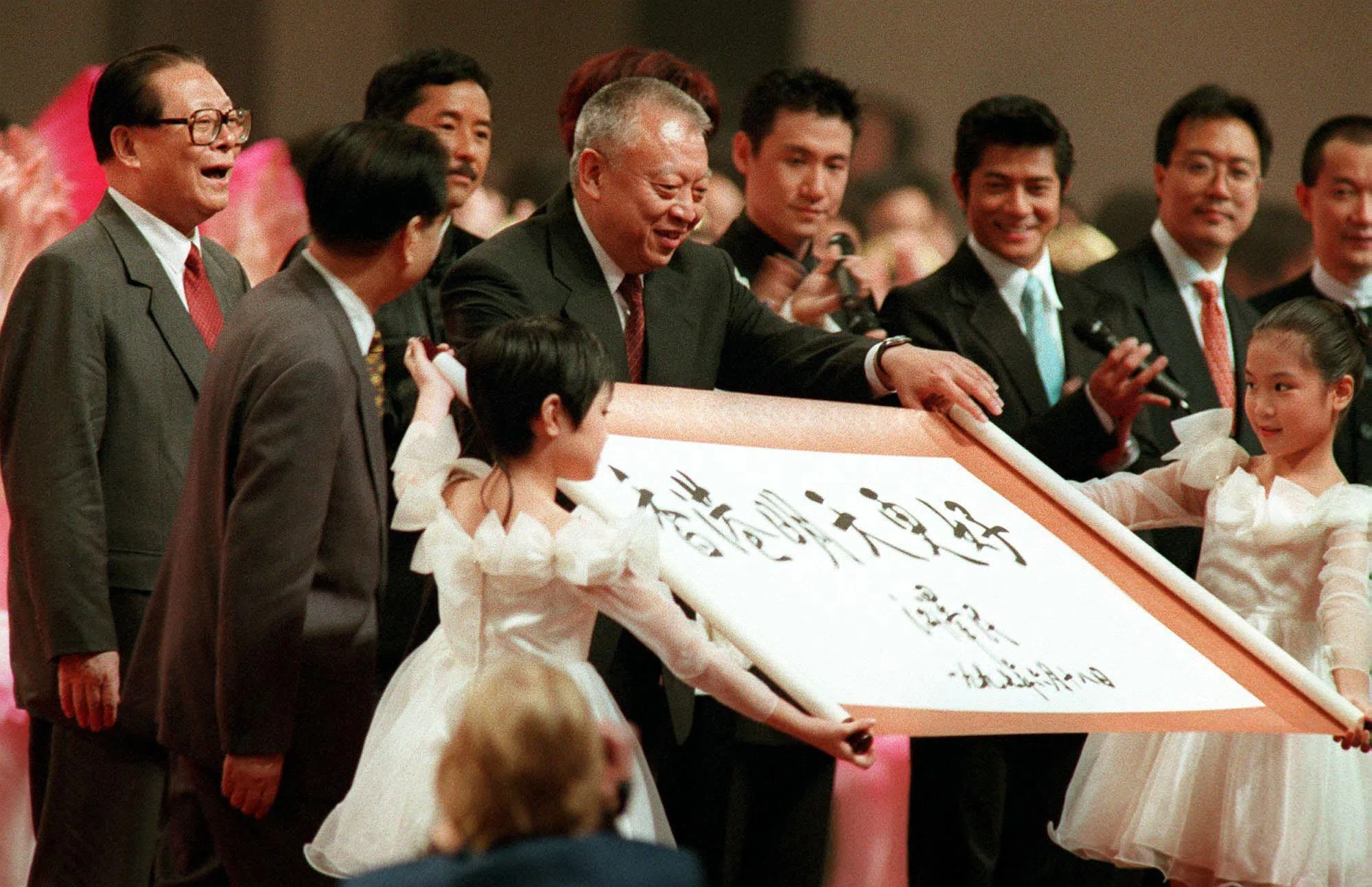 董建华（中）1997年7月1日在香港回归中国首日的庆祝活动上，展示了一幅由时任中国国家主席江泽民（左一）题字、寄语“香港明天更好”的书法作品。（法新社）