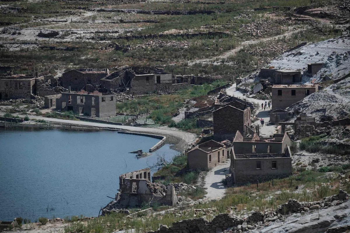 西班牙西北部奥伦塞省林多索水库水位最近骤降，曾被淹没的阿塞雷多村遗址露出水面，一些人趁机到此一游。1992年，当局为建造林多索水库而把阿塞雷多村的居民迁走，阿塞雷多村和另外三个村落最终被大水淹没。（法新社）