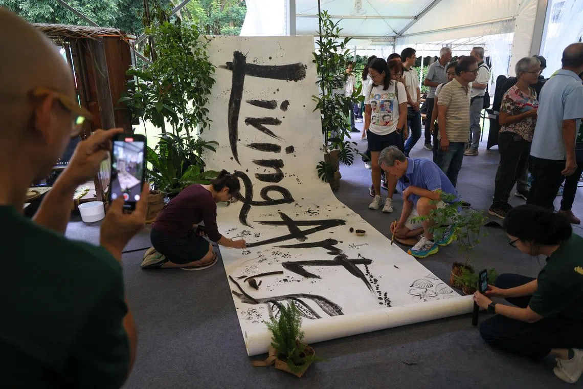 公众在“锦簇社区”20周年庆祝活动暨园艺节上参与大型艺术创作，把自然元素与书法绘画相结合。（张俊杰摄）
