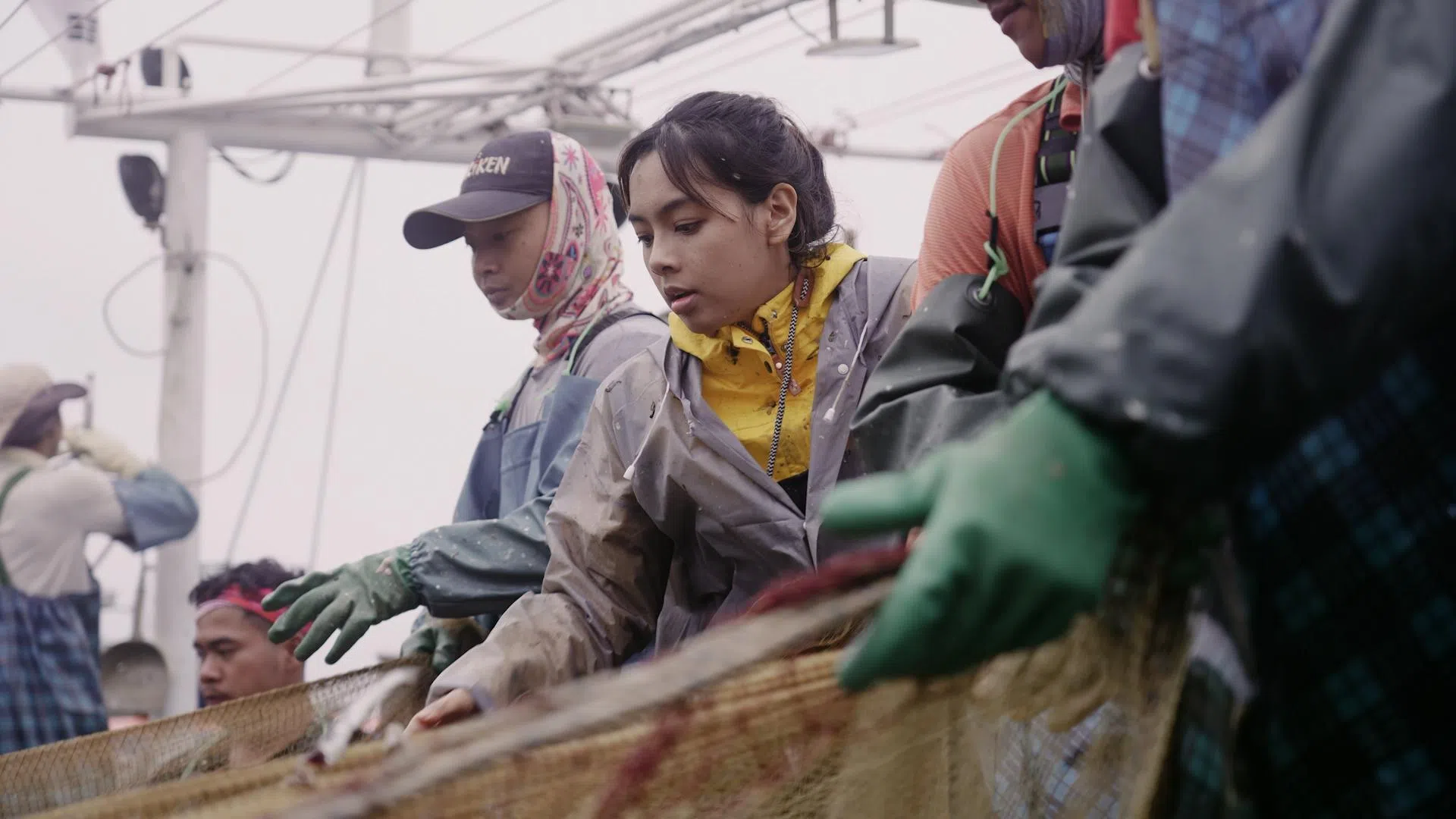 萧歆霓（中）和渔夫一起抖动鳀鱼，深刻感受到这份工作的辛苦。（新传媒提供）