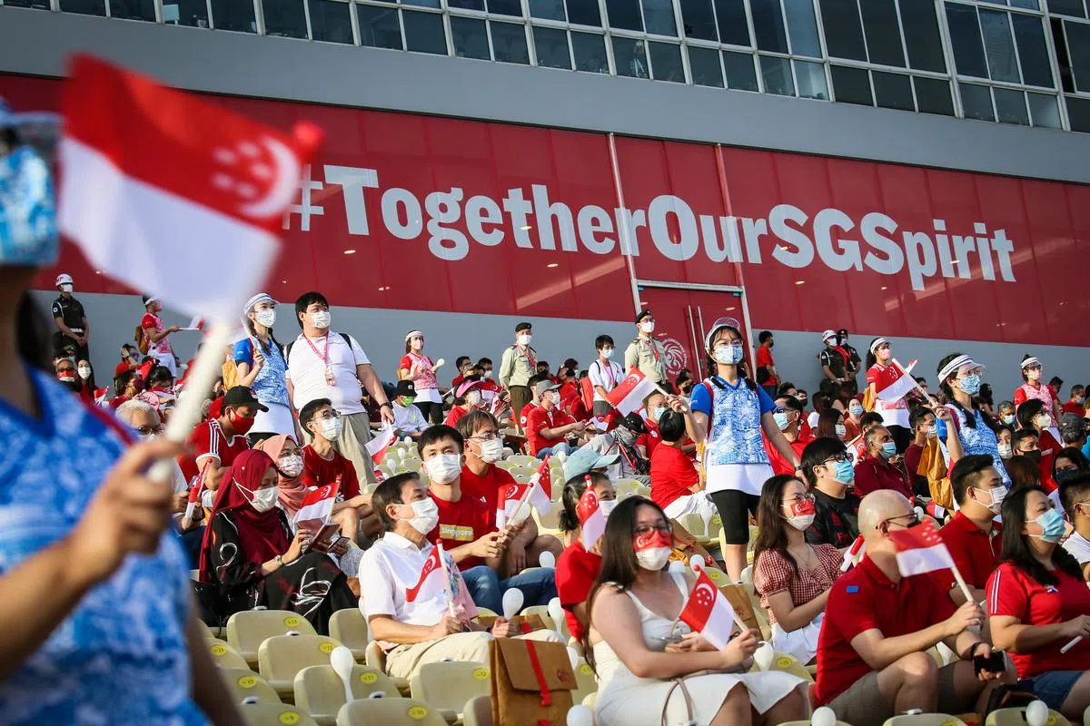 原本可容纳2万多人的观众席今年没有满座，只邀请1000名前线人员到场，但大家依然兴致高昂，时而挥舞手中的小国旗。（严宣融摄）