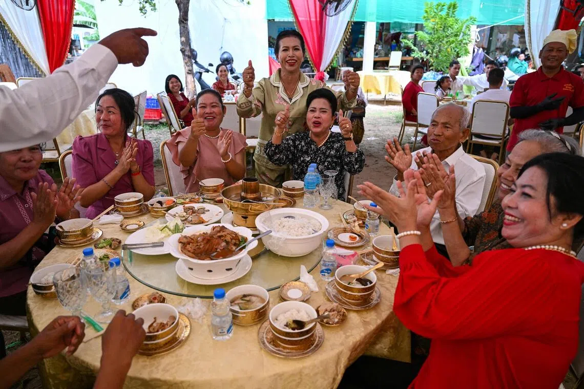 柬埔寨首都金边一场婚礼的宾客用餐时，听到泰柬领导人在吉隆坡签署和平协议的消息后一片欢腾。（法新社）