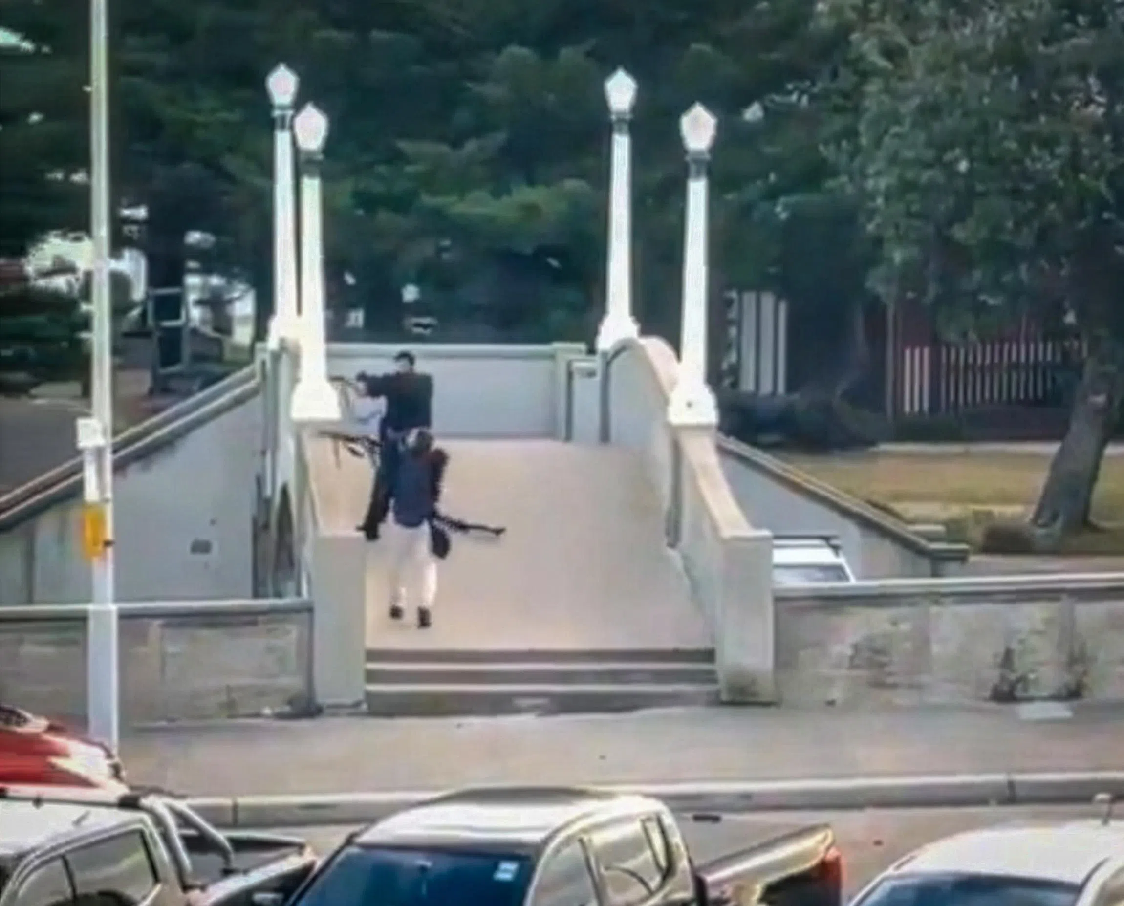 在社媒平台X上流传的视频显示，两名身穿黑衣的枪手在邦迪海滩一座小桥上开枪。（X平台）