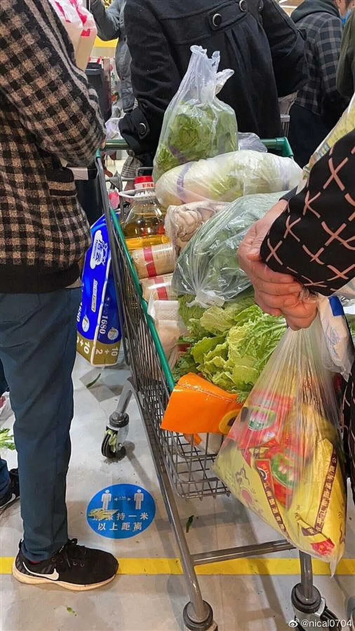 常州一家大型超市内挤满了抢购生活物资的市民，一位市民的推车内堆满了面条、蔬菜以及食用油。（互联网）