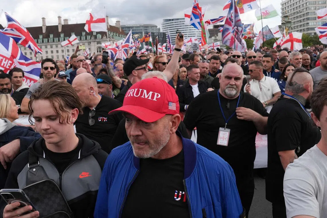 示威人群高举英国国旗和红白相间的英格兰圣乔治十字旗，还有人戴上美国总统特朗普的“让美国再次伟大”帽子，以示力挺反移民政策。（法新社）