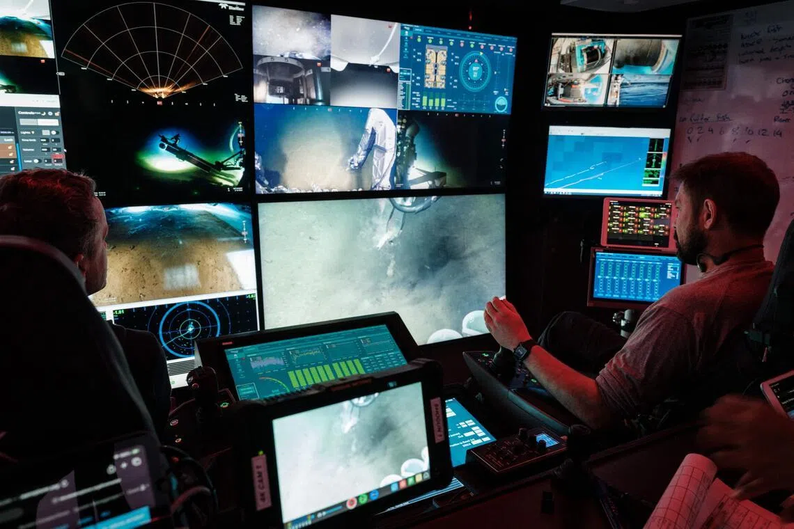 这张摄于1月10日的照片显示，科研船海洋探索号（OceanXplorer）的船员在印尼苏拉威西岛附近海域的控制室内操作一台遥控潜水器，向近1000米深的深海前进。（法新社）