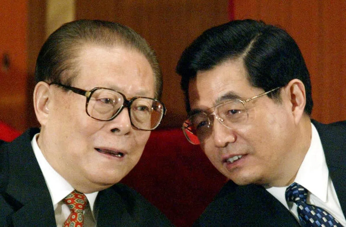 2003年3月，江泽民（左）按照当时宪法有关国家主席连任不超过两届的规定，又向胡锦涛移交了国家主席职务。图为2003年3月15日胡锦涛在全国人民代表大会上与江泽民交谈。（路透社）