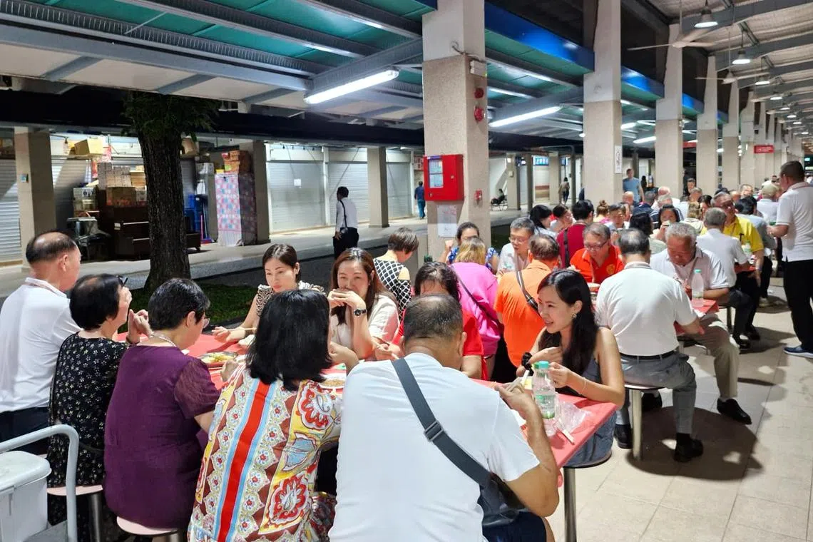 150多名潘氏宗亲在小贩中心并排坐着享用美食，场面热闹。（南洋潘氏总会提供）