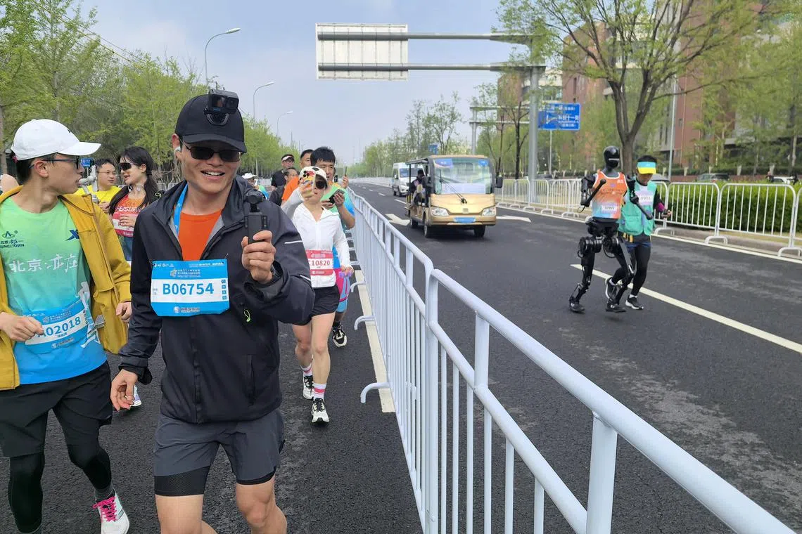 机器人不跟人类选手在同一赛道上跑马拉松，主要是安全考虑。图为人类选手比赛期间给围栏另一边的“天工Ultra”机器人拍照。（新华社）