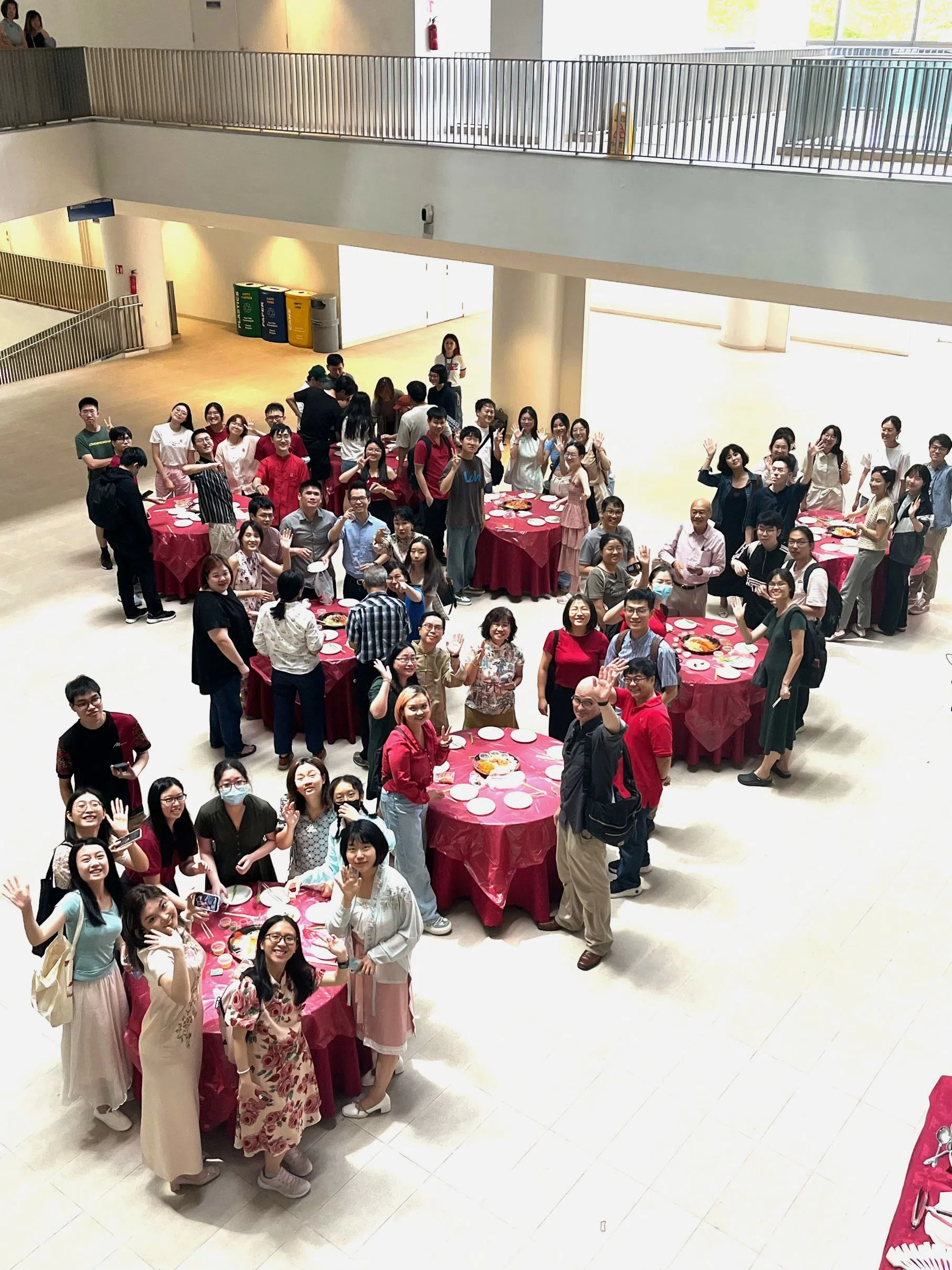 师生围着红色圆桌，跟着司仪的口令一边捞鱼生，一边齐声喊出贺词。（国大中文系同学会提供）