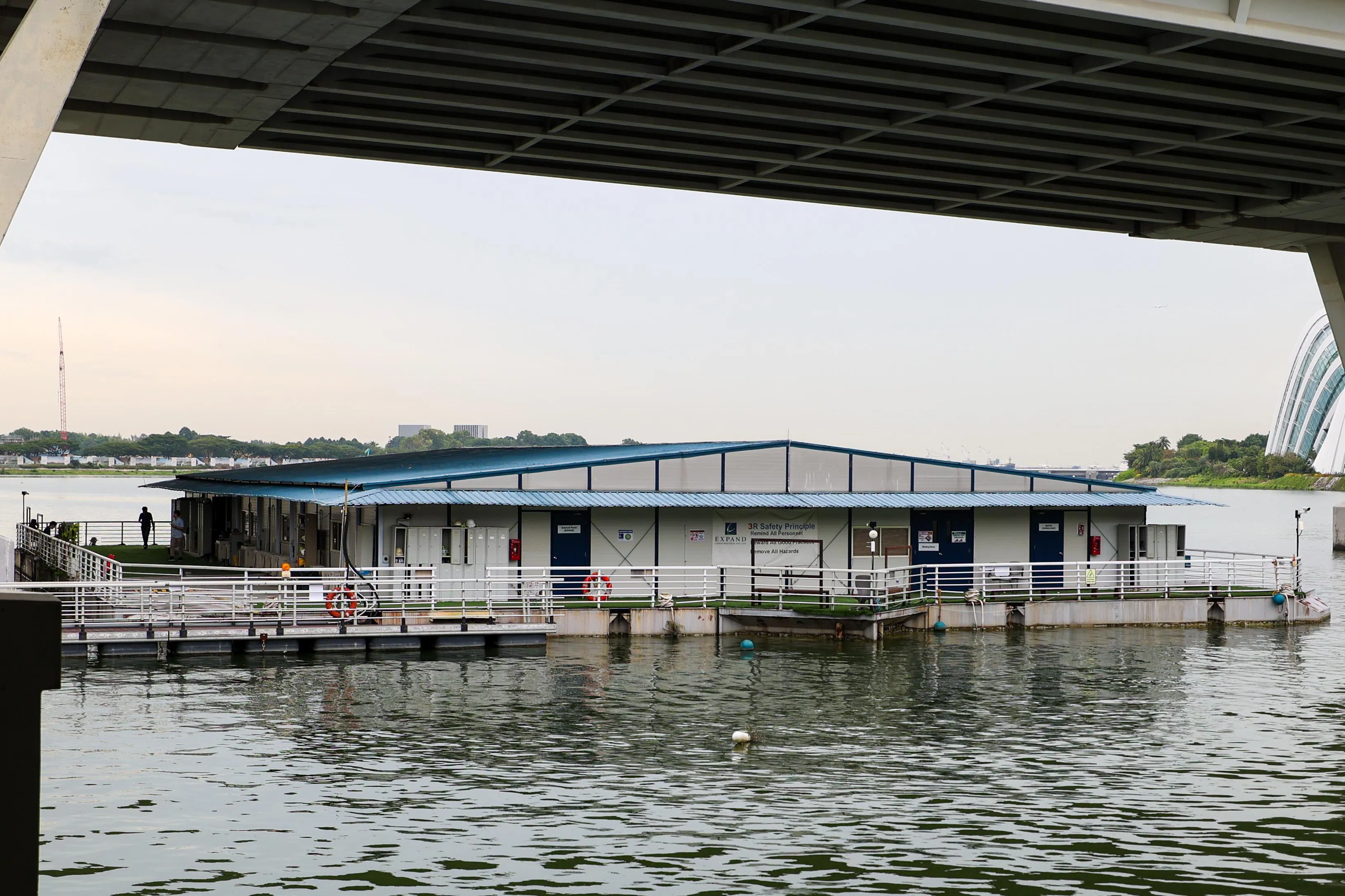 “浮动办公室”的员工对记者说，办公室上方的滨海湾薛尔思桥，像一把日夜撑开的大雨伞，为他们抵挡风雨。（林明顺摄）