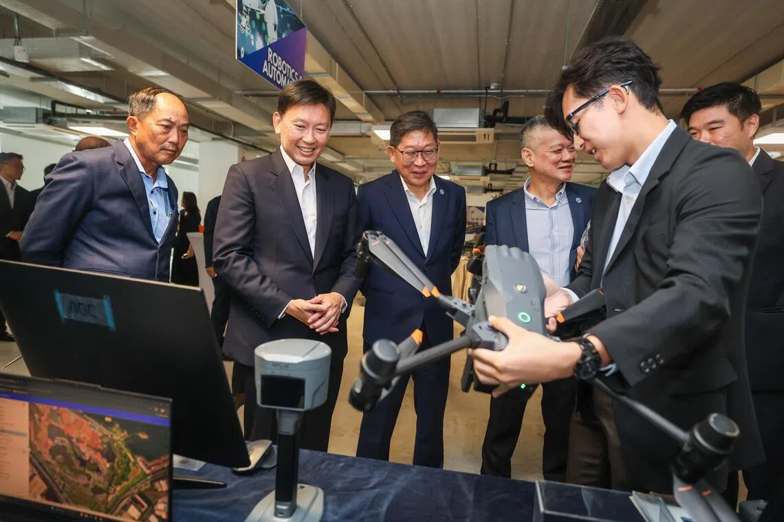 国家发展部长徐芳达（左二）星期五在新加坡建筑商公会建设中心参观供应商展示区时，了解科技企业如何利用无人机进行视觉测绘。（白艳琳摄）