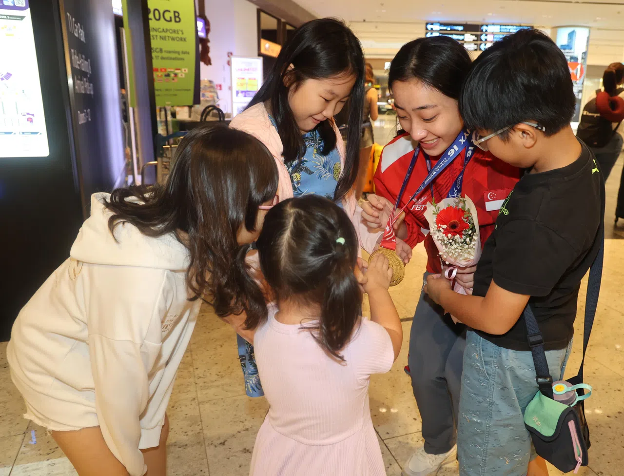 罗芝宁向表弟表妹们展示奖牌。（邬福梁摄）