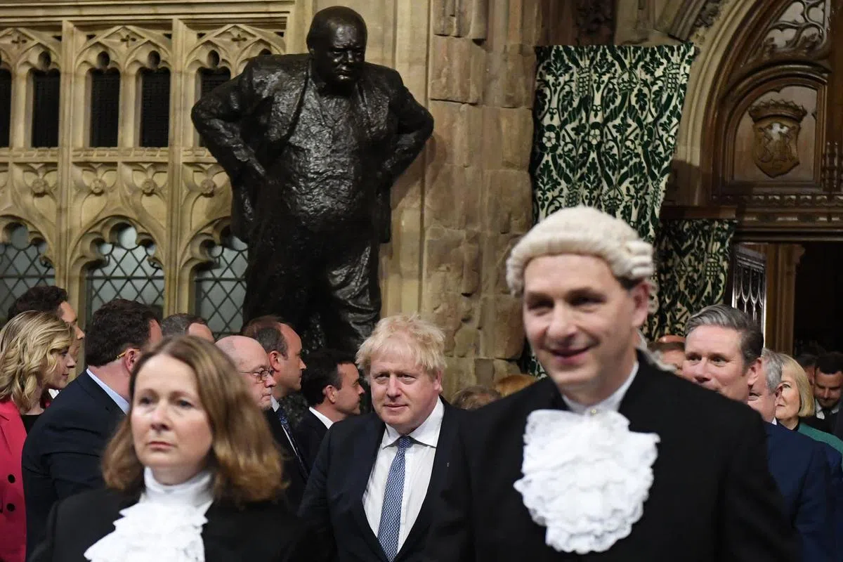 约翰逊（中）曾说，自己希望追随政治偶像温斯顿·丘吉尔（雕像）的脚步，成为一名举足轻重，带领英国人走出危机的领导人。（法新社）