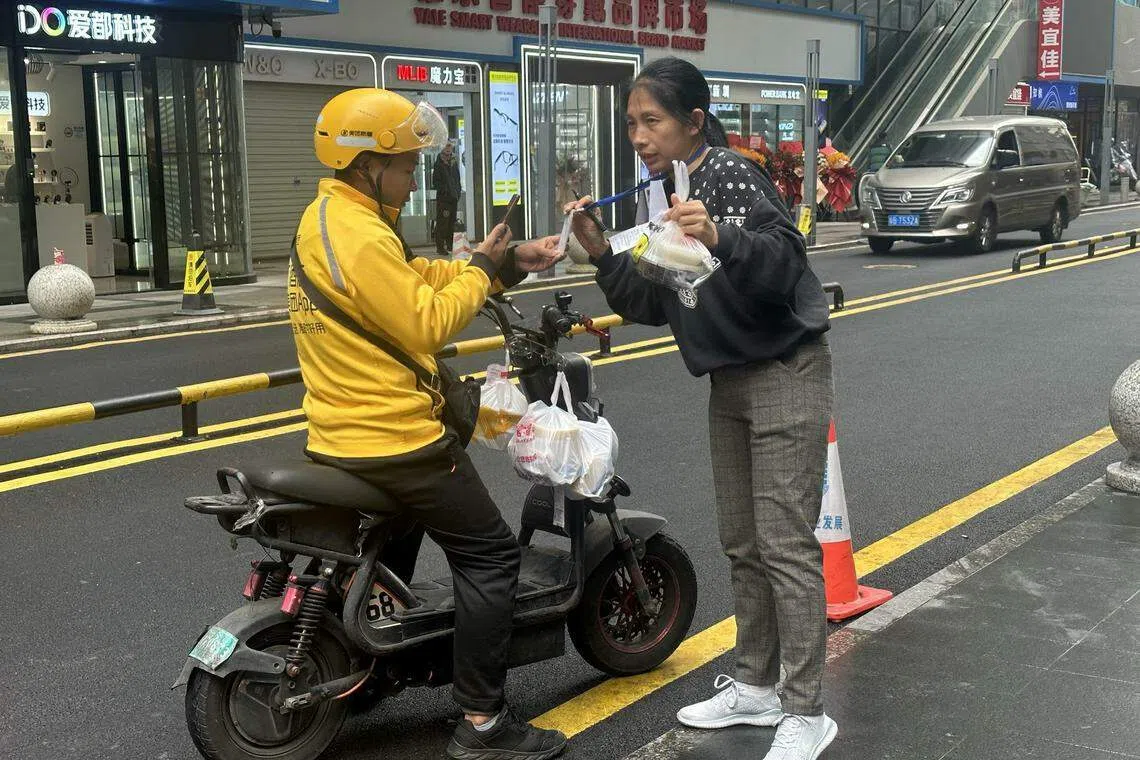 外卖骑手将外卖交给代送阿姨后，就可继续其他派送任务。（林煇智摄）