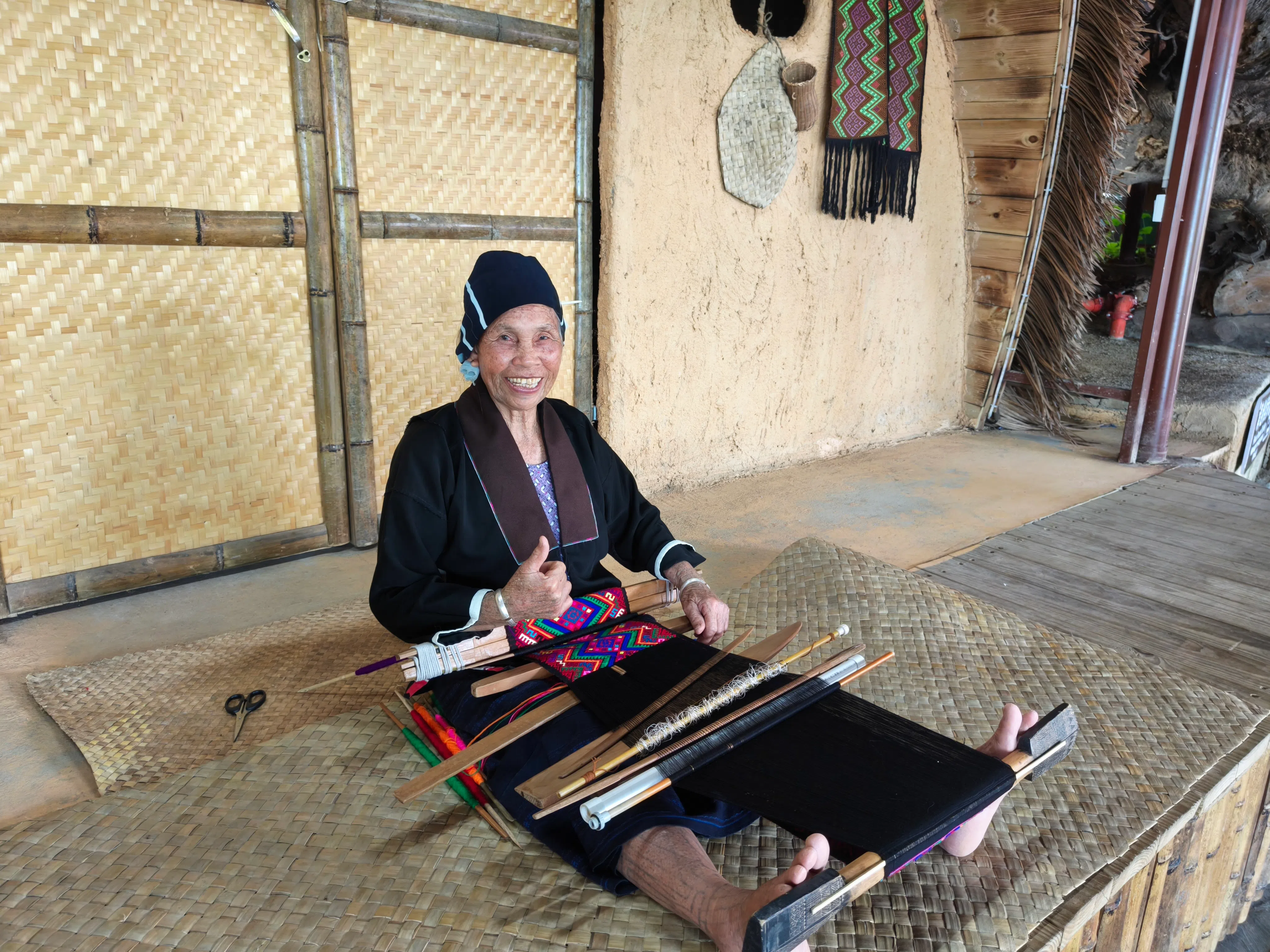 做织绣的黎族阿婆，腿上依稀可见年轻时的文身印记。（李雅歌摄）