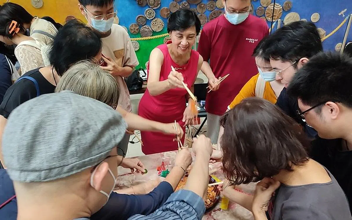 老师和同学们三五成群地聚在圆桌前捞鱼生，一边捞一边喊出祝福语，空气里洋溢着满满的祝福与温馨。（陈敏怡摄）