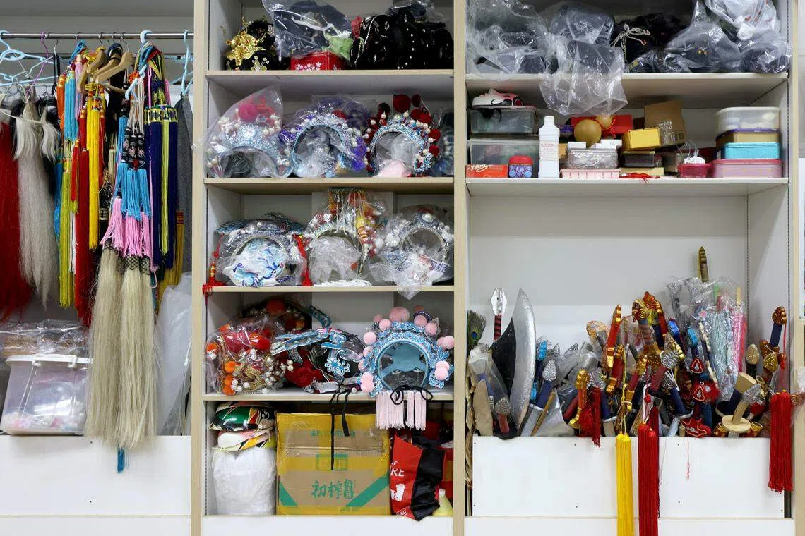 排练场的一面从地上至天花板用木板隔成大小不一的方柜，收纳服饰和盔头。（龙国雄摄）