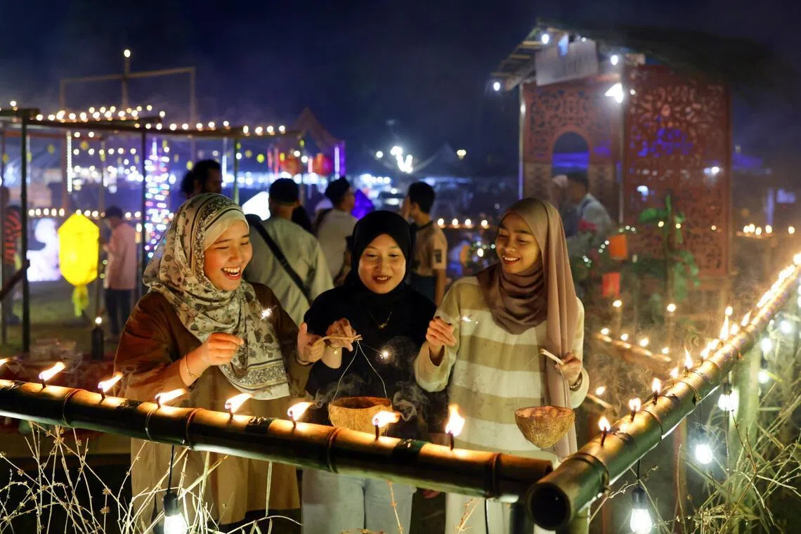 登嘉楼州政府举办的第六届开斋节油灯装饰比赛，吸引许多外地游客参与，也让年轻一代体验马来甘榜居民在开斋节前夕点油灯迎接游子回乡的传统习俗。（马新社）