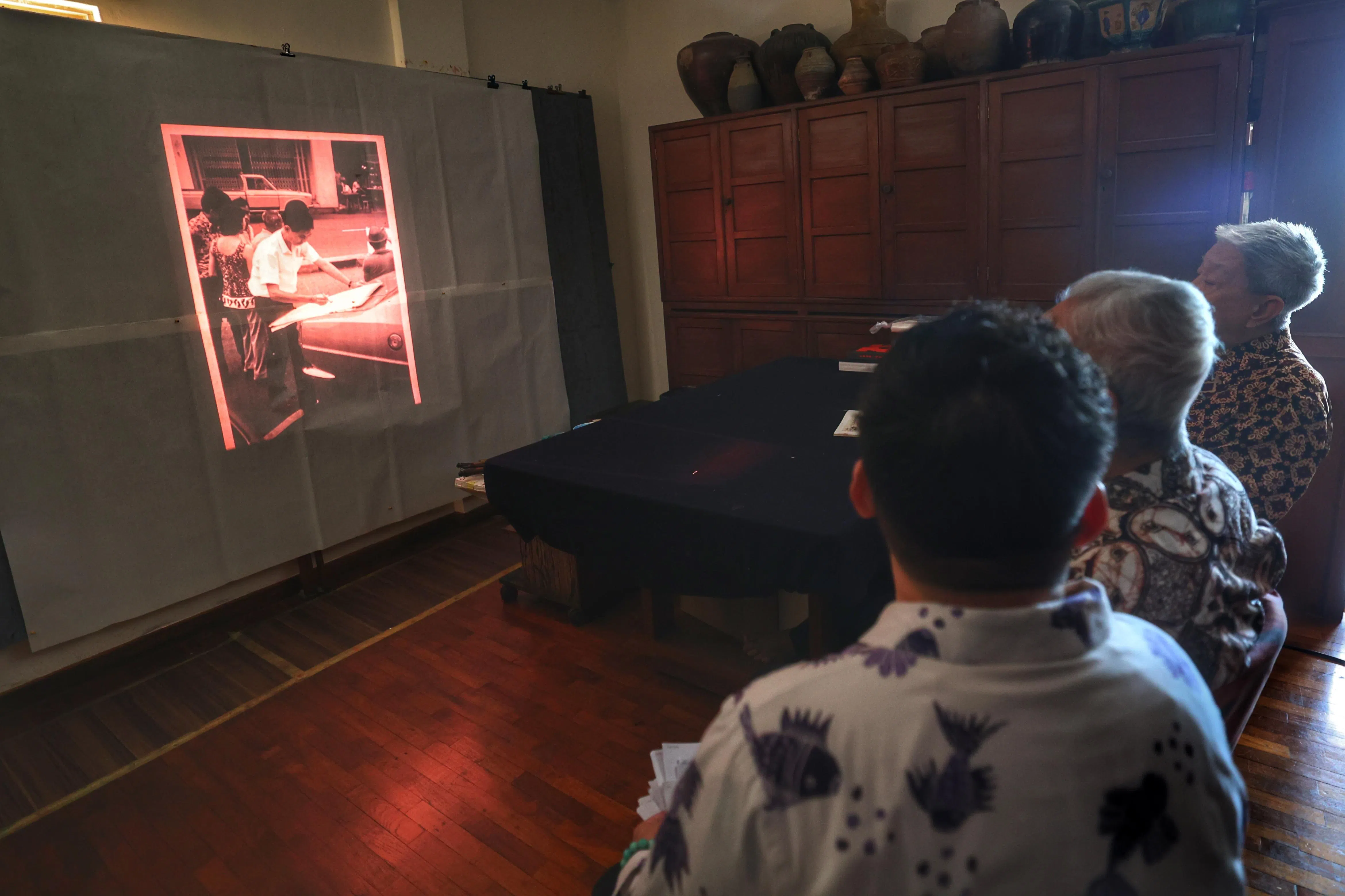 摄制团队将林子平老照片制成幻灯片，在黑暗的画室里陪他徜徉百年岁月之河。（郑一鸣摄）