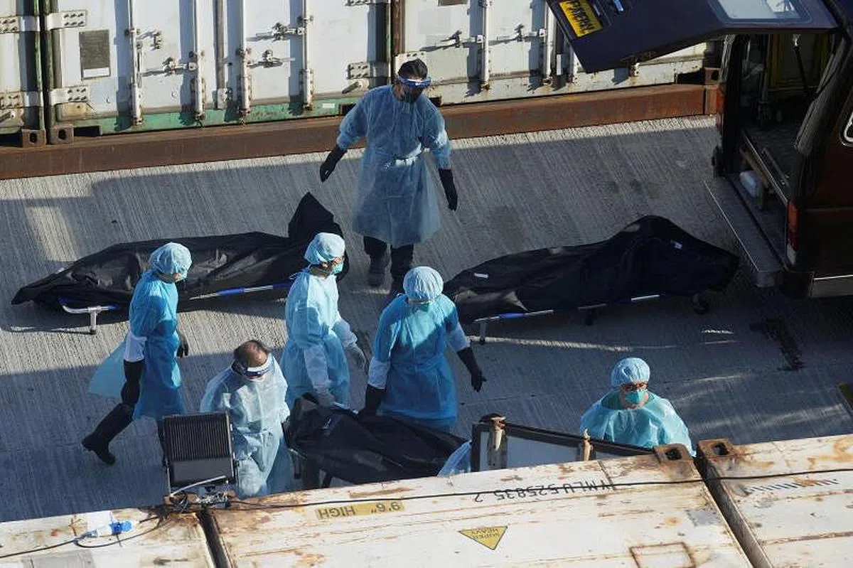 香港医护人员3月10日把冠病患者遗体转移至殡仪馆外的冷藏集装箱。（路透社）