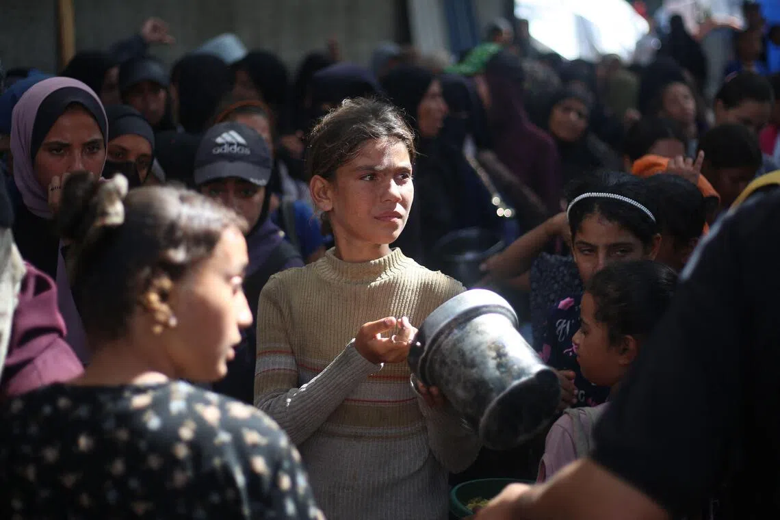 流离失所的巴勒斯坦人周二在加沙中部的努塞拉特难民营内，排队领取食物。据悉，由于担心停火协议可能会破裂，许多加沙人不敢把原本就有限的粮食一次过吃完，而是会把一部分留起来，省着慢慢吃。（法新社）