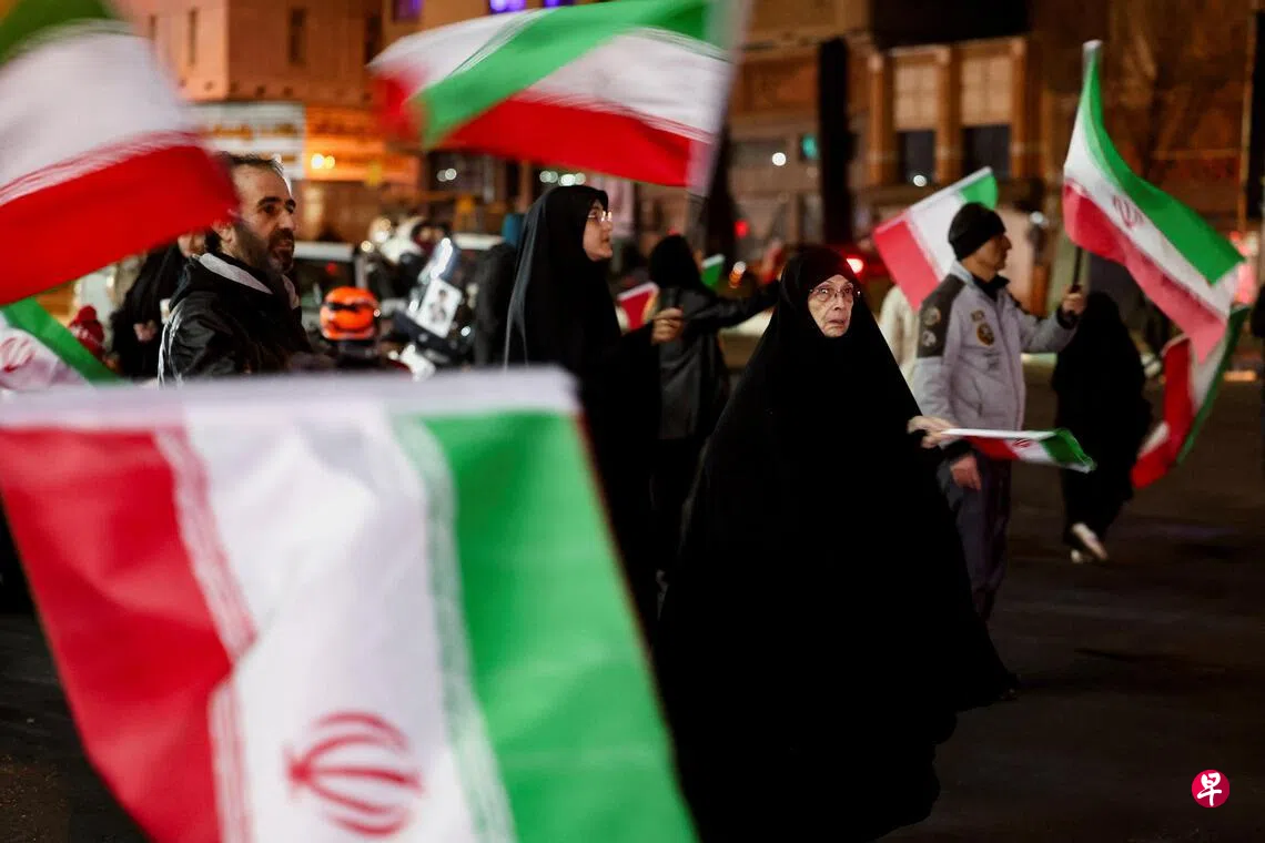 Image 15: 3月12日晚，在伊朗首都德黑兰，民众聚集在瓦利亚斯尔广场，挥舞国旗，表达对伊朗新最高领袖穆杰塔巴的支持。 （路透社）