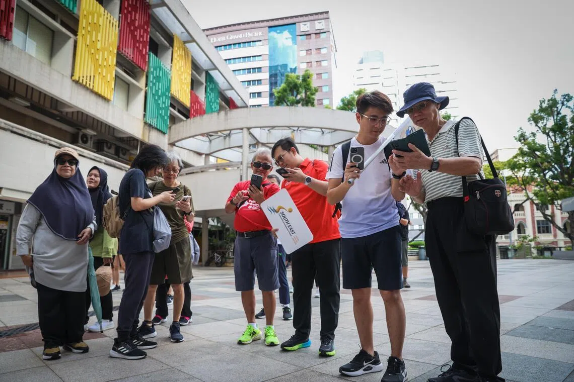  参与社理会齐步乐探计划（文化遗产版）的居民，在“书城”百胜楼外打卡。（白艳琳摄）